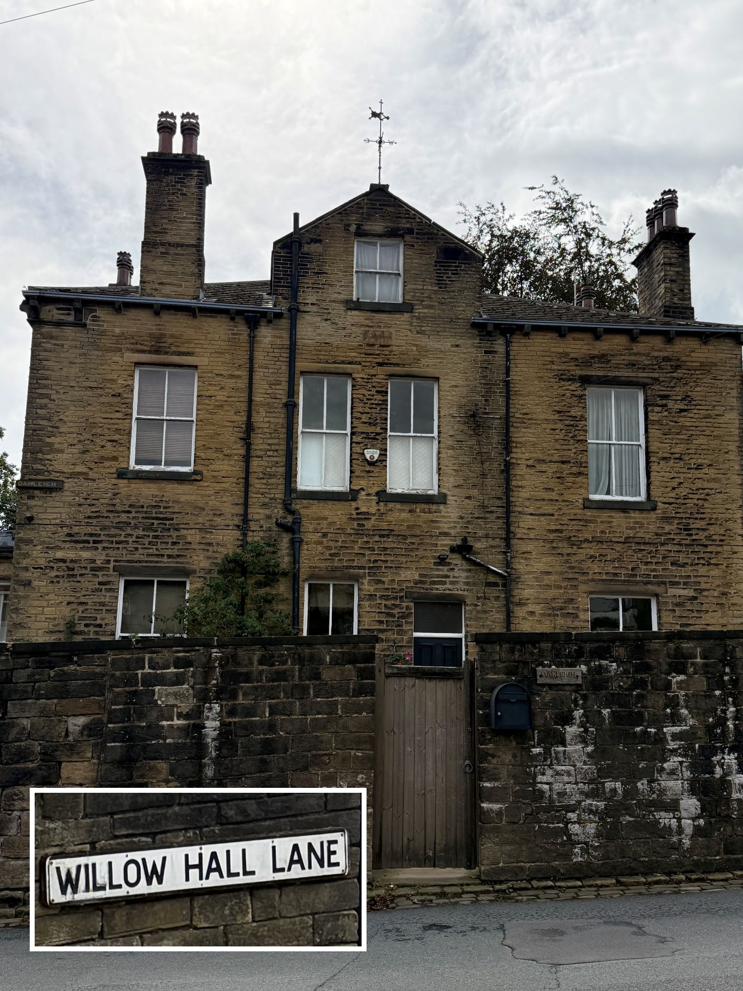 The rear of a double storey stone house with tall chimneys, a weathervane and sash windows, behind a high stone wall with a wooden gate. A nameplate reading &ldquo;Oakleigh&rdquo; is on the wall and the gatepost. An inset photo shows a street sign reading &ldquo;Willow Hall Lane&rdquo;.