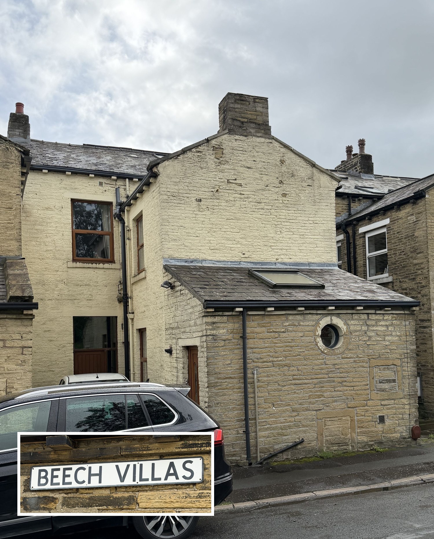 The side of a stone house, painted cream, with a lower stone extension with a round window, seen from the street with a dark car parked in front. An inset photo shows a street sign reading &ldquo;Beech Villas&rdquo;.